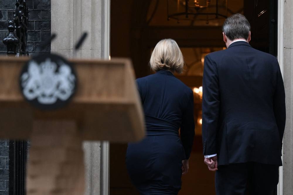Britain's Prime Minister Liz Truss and her husband Hugh O'Leary get inside 10 Downing Street, in central London, on October 20, 2022 following a statement to announce her resignation. — AFP pic