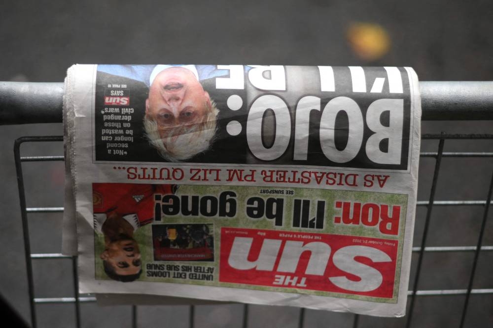 A copy of The Sun newspaper featuring former prime minister Boris Johnson lies on a barrier outside 10 Downing Street in central London on October 21, 2022. - Contenders bidding to succeed Prime Minister Liz Truss canvassed for support with her predecessor Boris Johnson reportedly considering a sensational comeback, while opposition parties demanded an early general election to end months of political chaos. — AFP pic