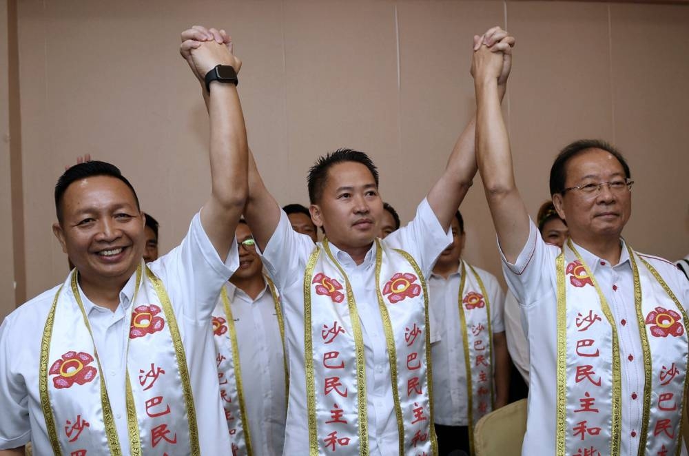 PKDM president Datuk Peter Anthony (centre) joins hands with Datuk Wetrom Bahanda (left) at a PKDM event at the Hakka Hall in Kota Kinabalu, October 21, 2022. — Bernama pic 