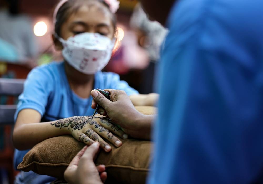 N. Jeevana, 9, gets a henna design drawn on her hand by a henna artist in preparation for Deepavali celebrations at Little India in Ipoh October 22, 2022. — Bernama pic