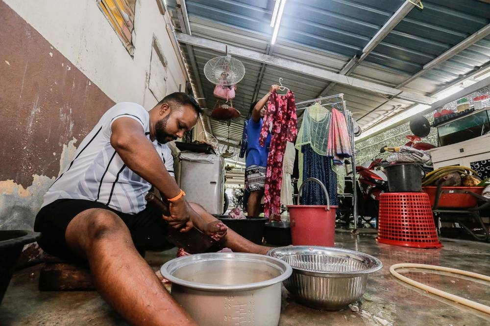 J. Siva (left), 42, preparing lamb meat while his relative C. Kumunthini (right), 38, hangs the laundry as they prepare for the upcoming Deepavali celebration in Sepang October 23, 2022. — Picture by Sayuti Zainudin