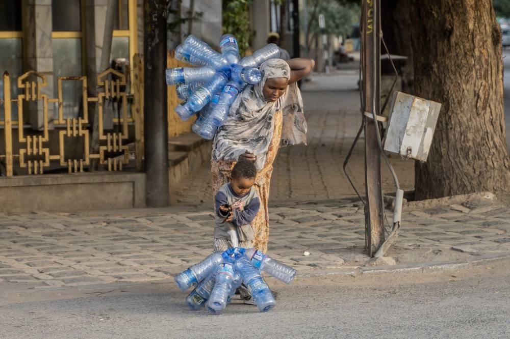 A woman carrying plastic bottles helps her child in Dire Dawa, Ethiopia, on October 23, 2022. — AFP pic