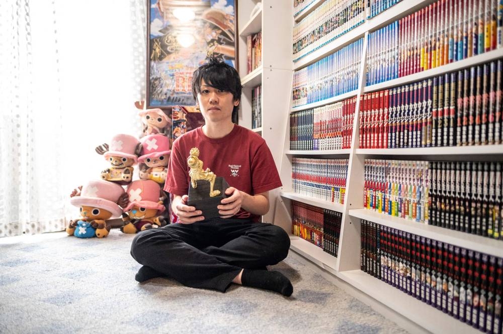 Shohei Sato poses a photo with a trophy from the 'One Piece' knowledge king contest after an interview with AFP in his house in Tokyo September 18, 2022. — AFP pic