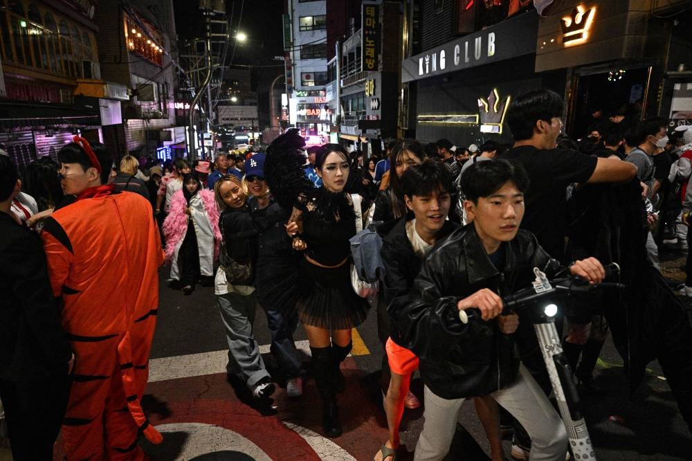 Revellers gather in the neighbourhood of Itaewon in Seoul on October 30, 2022, near to the location where a Halloween stampede took place. - More than 140 people were killed on October 29 and some 150 were injured in a horrific stampede in central Seoul when a large crowd celebrating Halloween crammed into a narrow street, officials said. — AFP pic