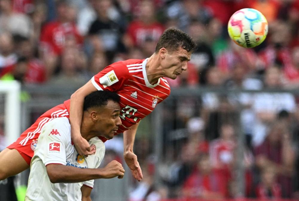 Bayern Munich's French defender Benjamin Pavard (top) and Mainz' Austrian forward Karim Onisiwo vie for the ball during the German first division Bundesliga football match Bayern Munich v Mainz 05 in Munich on October 29, 2022.— AFP pic