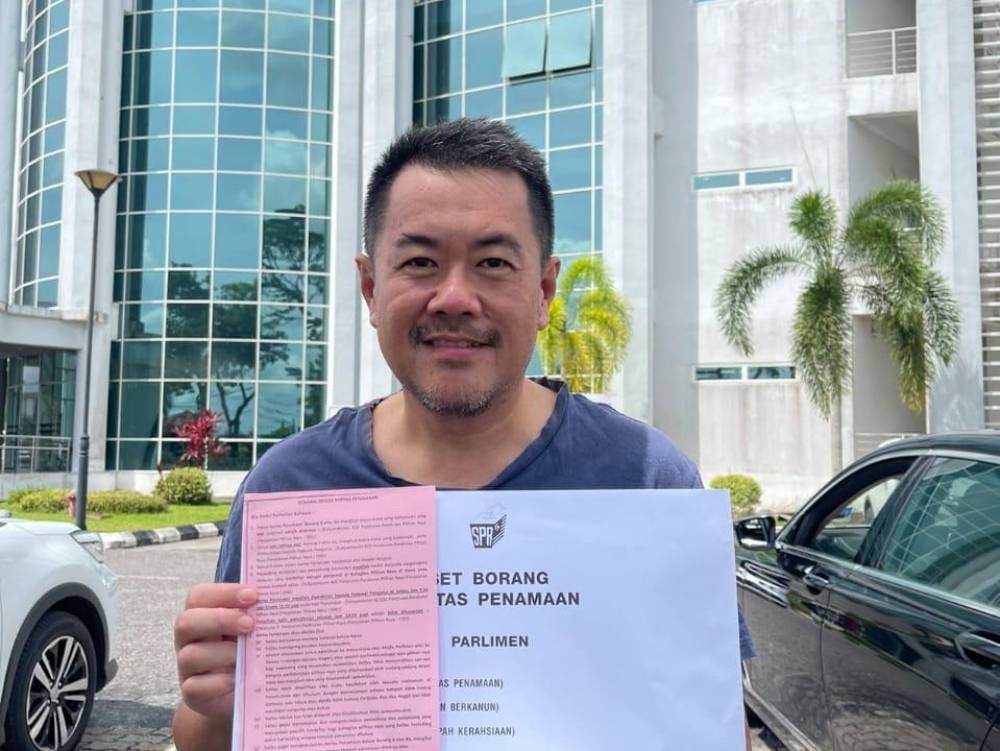 Daniel Sng shows his nomination papers. — Borneo Post pic