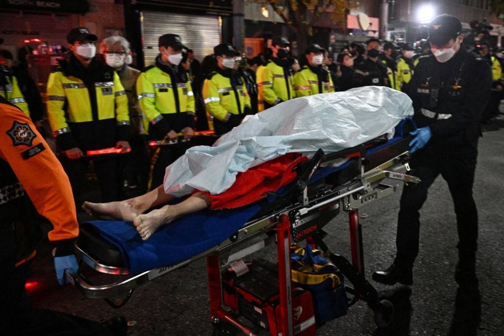 The body of a victim of a Halloween stampede, which left more than 140 people dead, is carried on a stretcher in the neighbourhood of Itaewon in Seoul on October 30, 2022. More than 140 people were killed on October 29 and some 150 were injured in a horrific stampede in central Seoul when a large crowd celebrating Halloween crammed into a narrow street, officials said. — AFP pic