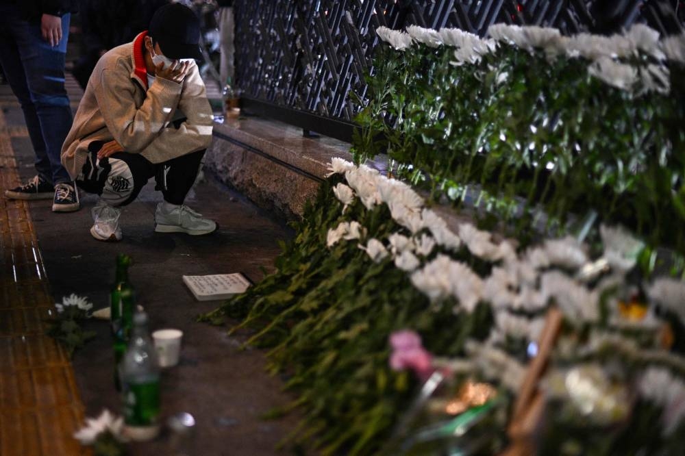 A man reacts as he squats next to a makeshift memorial outside the Itaewon subway station in the district of Itaewon in Seoul October 30, 2022, the day after a Halloween stampede in the area. — AFP pic 