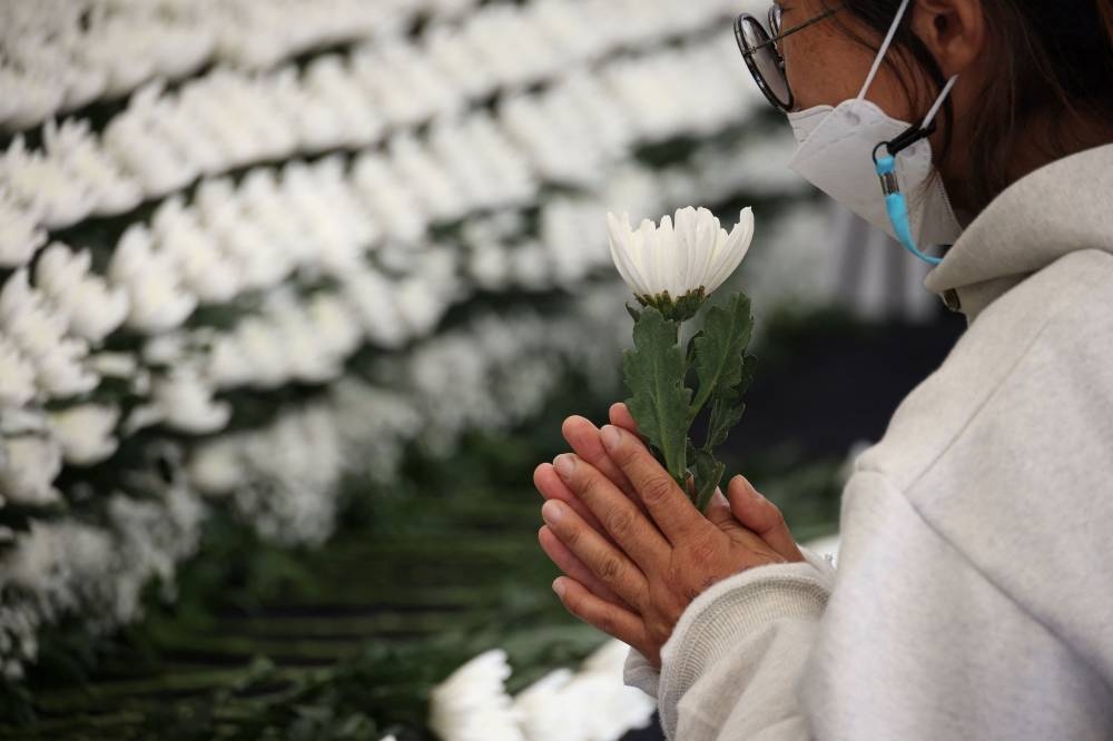 A person pays their respects at a group memorial altar for victims of a stampede that happened during Halloween festivities, in Seoul, South Korea, October 31, 2022. — Reuters pic