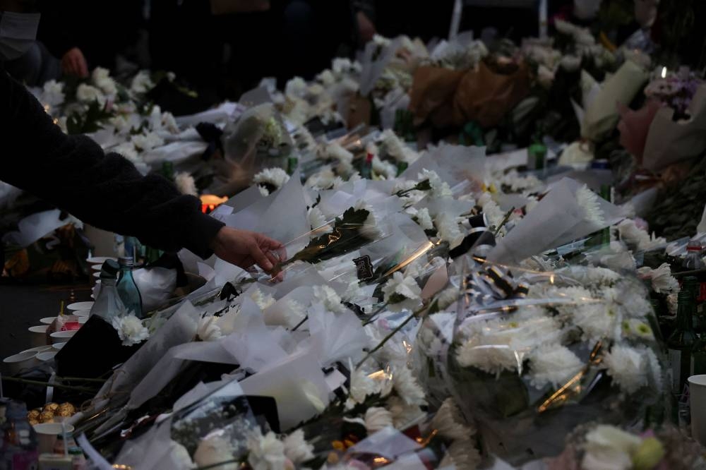 A person lays floral tribute near the scene of a crowd crush that happened during Halloween festivities, in Seoul October 31, 2022. — Reuters pic