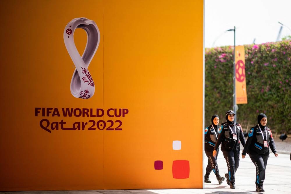 Policewomen walk past FifaWorld Cup signs as they arrive at the Main Media Centre in Doha on October 31, 2022. — AFP pic