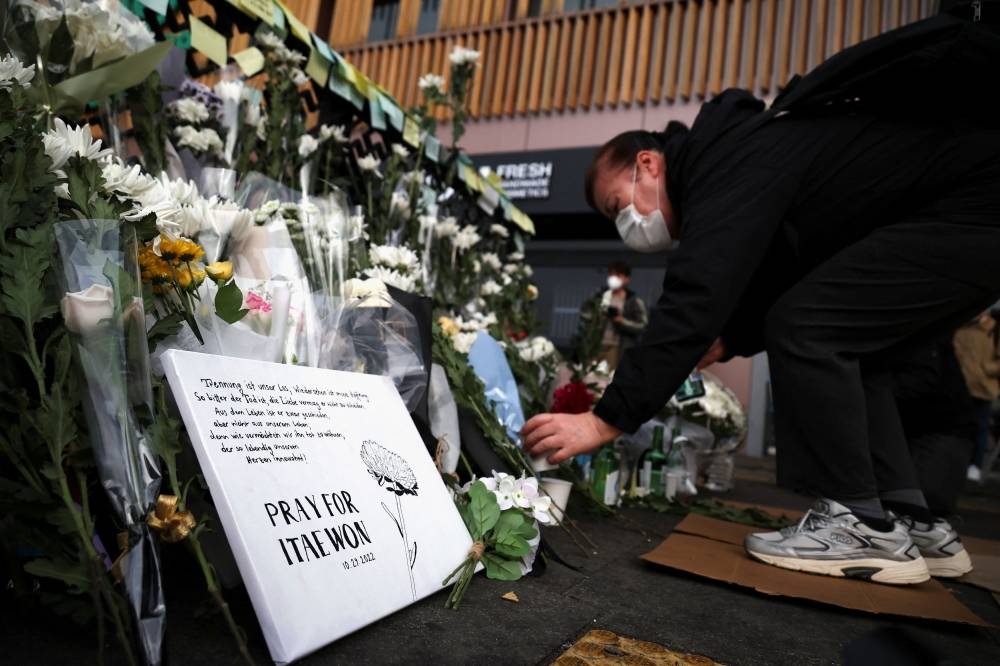 A woman places a floral tribute near the scene of a crowd crush that happened during Halloween festivities, in Seoul November 1, 2022. — Reuters pic