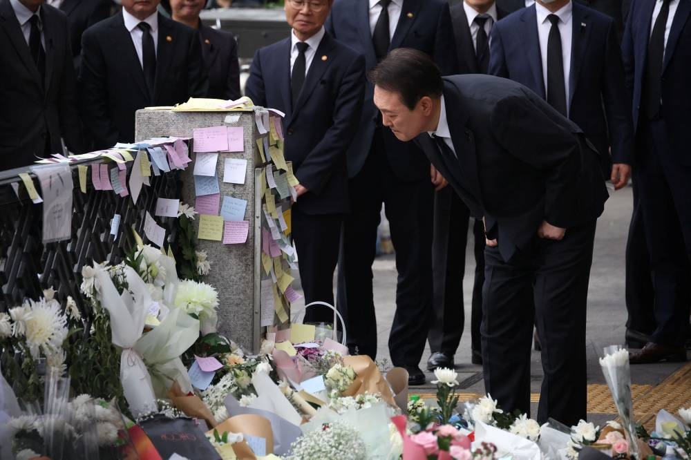 South Korean President Yoon Suk-yeol reads messages placed by mourners as he visits the scene of a crowd crush that happened during Halloween festivities, in Seoul November 1, 2022. — Reuters pic