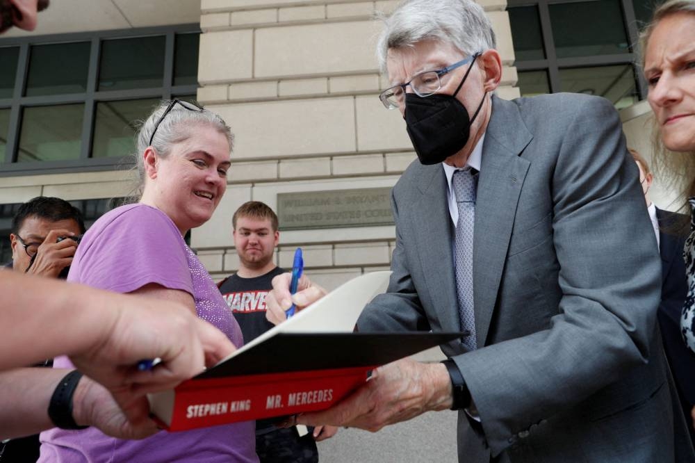 Novelist Stephen King gives autographs as he leaves the US District Court on the day he testifies in an antitrust case against a publisher merger, in Washington August 2, 2022. — Reuters pic