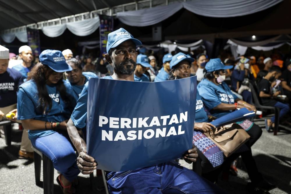 A man holds up a placard featuring the Perikatan Nasional logo at the launch of the coalition's election machinery in Sungai Besar November 3, 2022. — Bernama pic