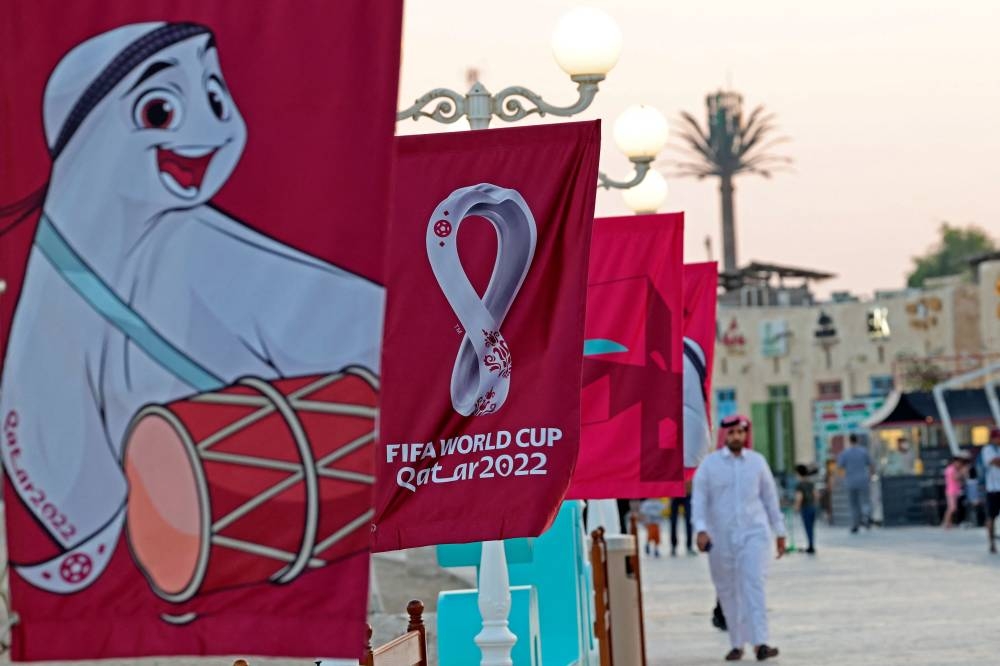 People walk past FifaWorld Cup banners at a beach in Doha on November 3, 2022. — AFP pic