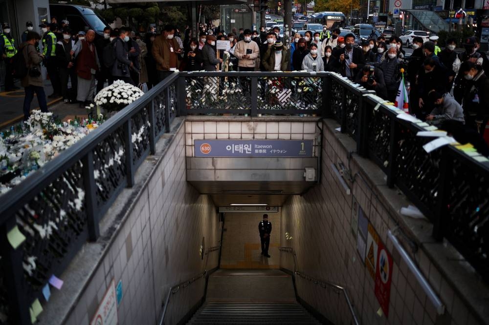A police officer stands guard at the exit of a subway station as people gather to pay their respects following a crowd crush that happened during Halloween festivities, in Seoul, South Korea, November 1, 2022. — Reuters pic