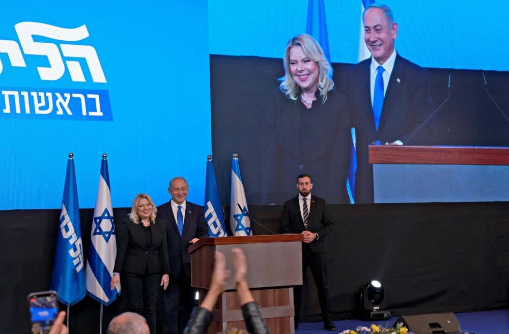 Israel's ex-premier and leader of the Likud party Benjamin Netanyahu, flanked by his wife Sara, addresses supporters at campaign headquarters in Jerusalem early on November 2, 2022, after the end of voting for national elections. — AFP pic