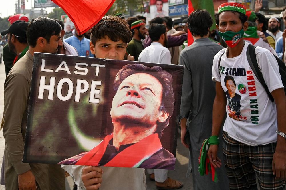 Supporters of former Pakistani prime minister Imran Khan, take part in a protest near the container truck a day after the assassination attempt on Khan, at the cordoned-off site of a gun attack in Wazirabad November 4, 2022. — AFP pic