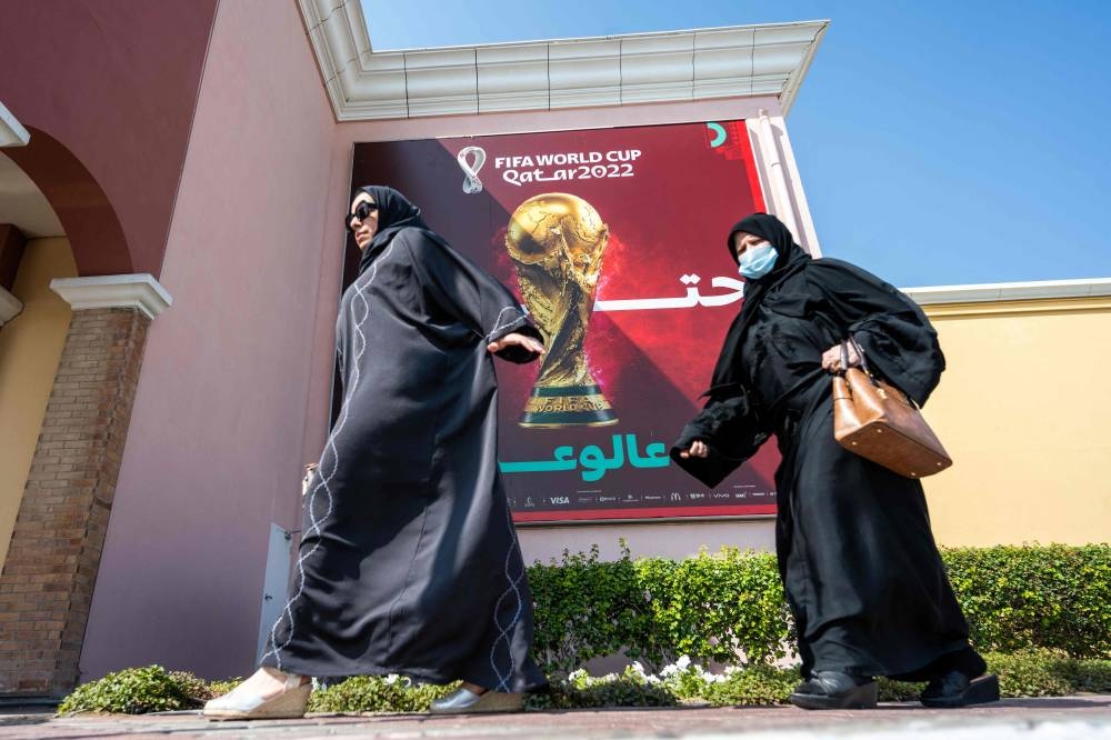 Women walk past a FIFA World Cup banner in Doha on November 3, 2022, ahead of the Qatar 2022 FIFA World Cup football tournament. — AFP pic