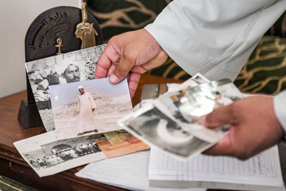 In this file photo taken on August 1, 2022, antiquities excavator Mostafa Abdo Sadek shows off portraits of his family members and ancestors during an interview in Saqqara, southwest of Egypt's capital. — AFP pic