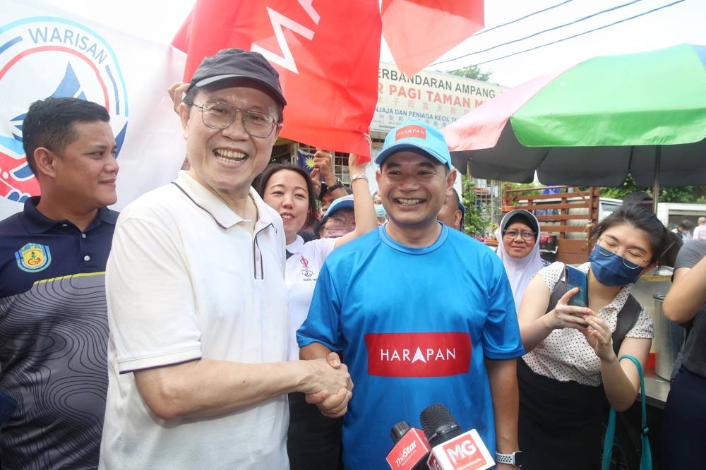 Parti Warisan’s Tan Sri Ong Tee Keat and Pakatan Harapan’s Rafizi Ramli take a picture together during their campaign walkabout at the Taman Muda morning market, November 6 ,2022. — Picture by Choo Choy May