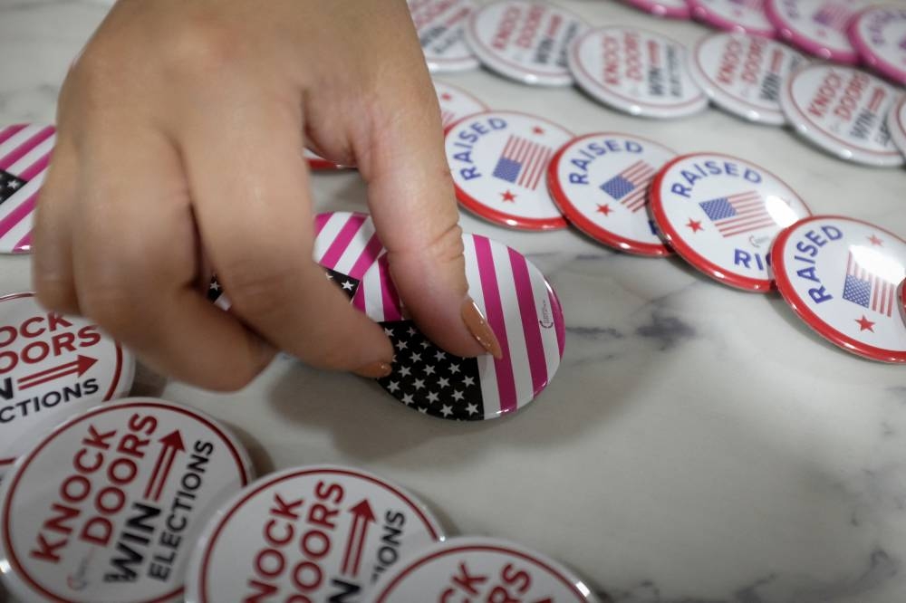 An attendee picks up pins as she arrives for a rally with Florida Governor Ron DeSantis ahead of the midterm elections, in Hialeah, Florida November 7, 2022. ― Reuters pic