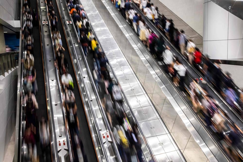 This photo taken on October 20, 2022 shows people making on escalators at a train station in Hong Kong. — AFP pic