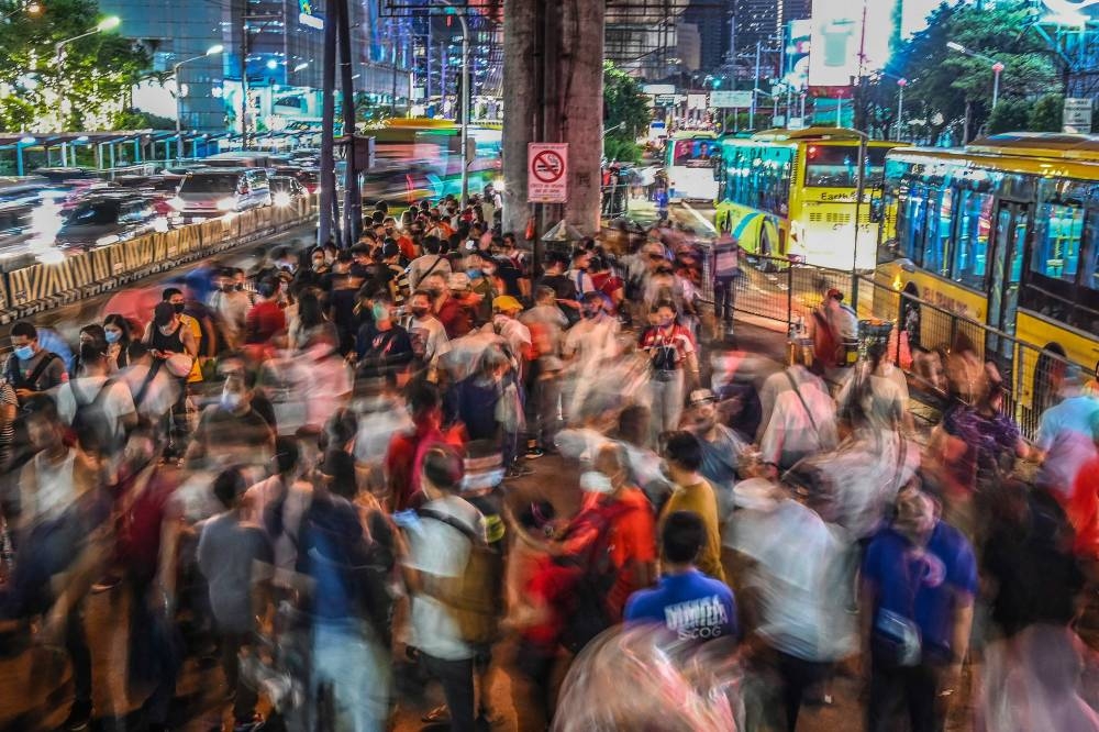 This photo taken on October 14, 2022 shows commuters waiting for buses to arrive at a station in Mandaluyong, Metro Manila. — AFP pic