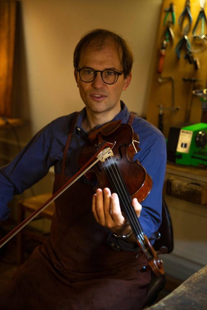 This file photo taken on October 21, 2022 shows French bow maker Edwin Clement playing violin in his studio in Paris. — AFP pic