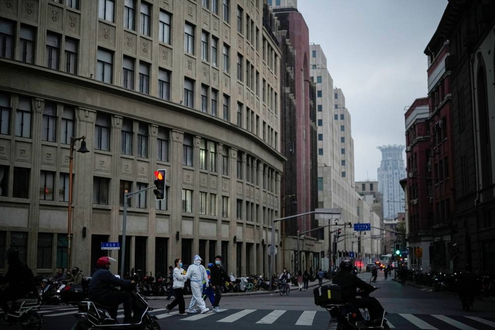 A worker in a protective suit walks across a street, following a coronavirus disease (COVID-19) outbreak in Shanghai, China, November 10, 2022. — Reuters pic