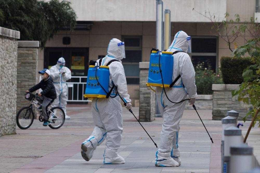 Workers in protective suits spray disinfectant in a residential compound that was placed under lockdown as outbreaks of Covid-19 continue in Beijing, China November 9, 2022. ― Reuters pic