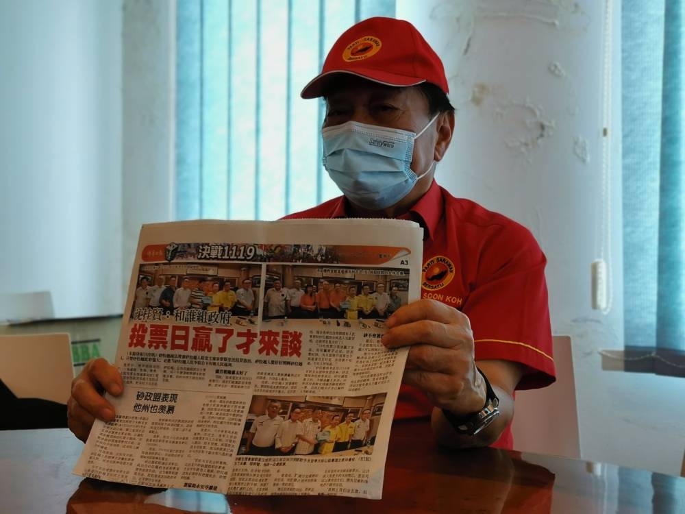 Wong shows the See Hua Daily News report during the press conference. — Borneo Post pic