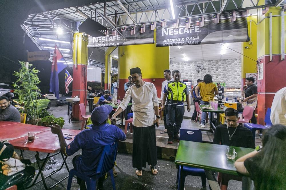 BN candidate Mohd Helmy Abd Latiff shakes hands with customers at the Al Haddad restaurant, during a campaign walkbaout in Muar, November 6, 2022. — Picture by Hari Anggara