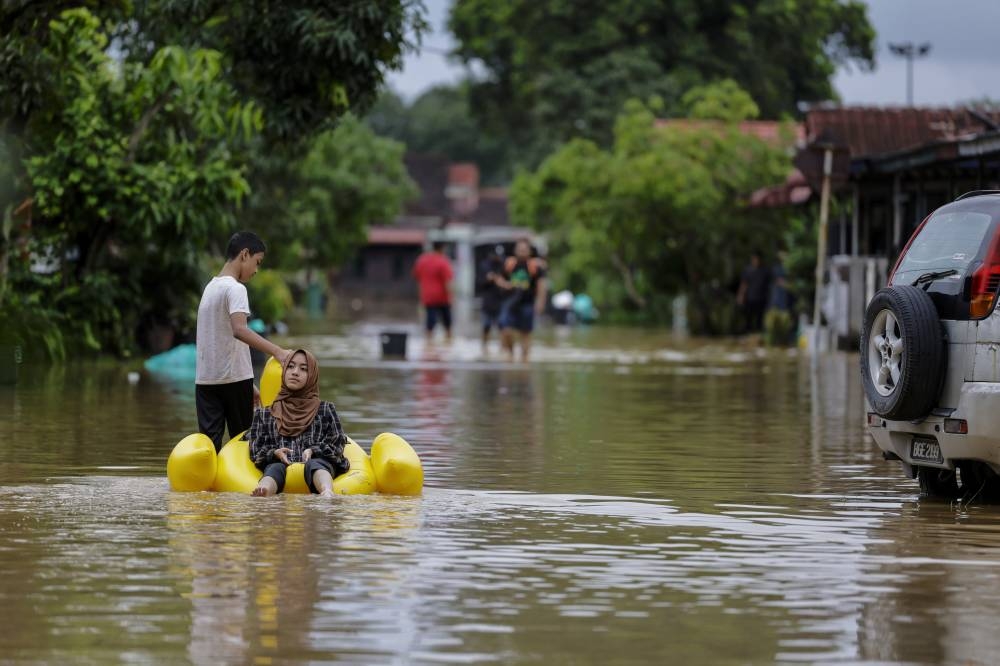 A brother and sister use a float to navigate the floodwater in Klang, November 11, 2022. — Bernama pic 