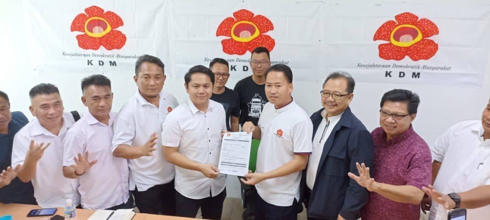 Independent candidate for Tenom Riduan Rubin (3rd, left) with PKDM president Datuk Peter Anthony (3rd, right) hold up the party’s membership form. — Picture from social media 