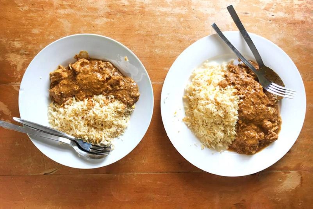 Versare un po' di cremoso pollo al curry su ogni piatto di riso con uova dorate.