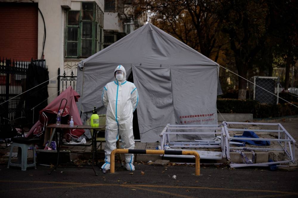 A pandemic prevention worker in a protective suit stands outside an apartment compound that was placed under lockdown as outbreaks of the coronavirus disease continue in Beijing, November 12, 2022. ― Reuters pic
