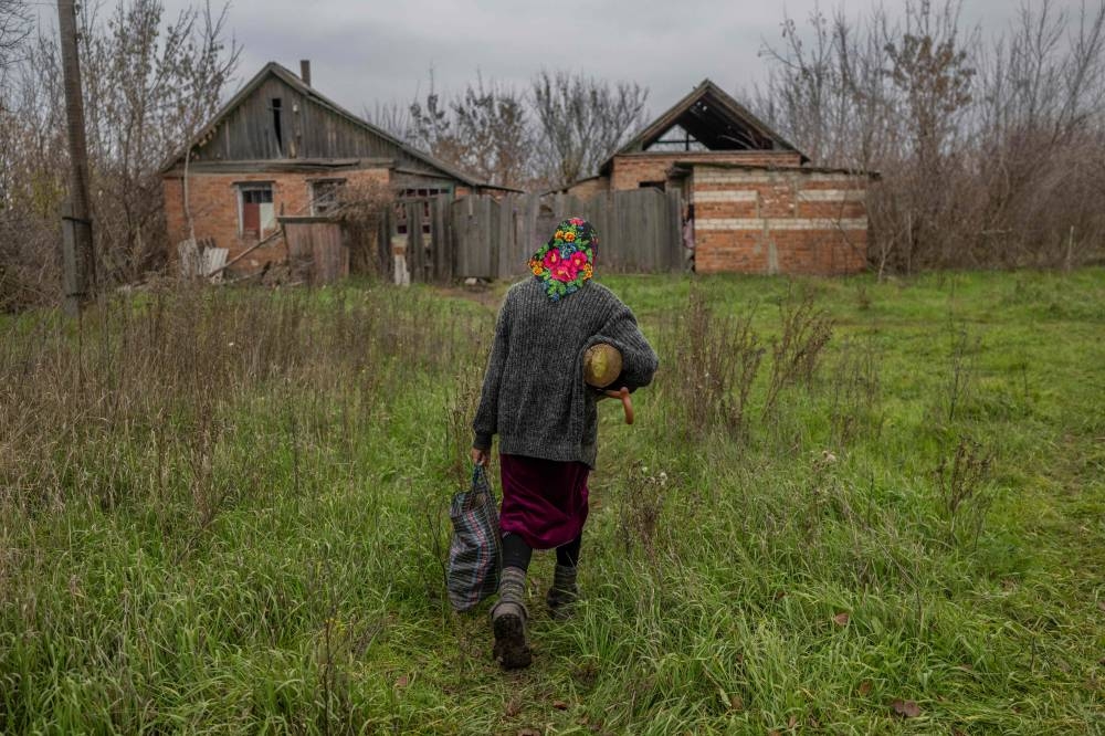 Ukrainian woman comes back home with some wood in Siversk, a town in eastern Ukraine hit by Russian forces couple of days ago, on November 11, 2022, amid the Russian invasion of Ukraine. ― AFP pic