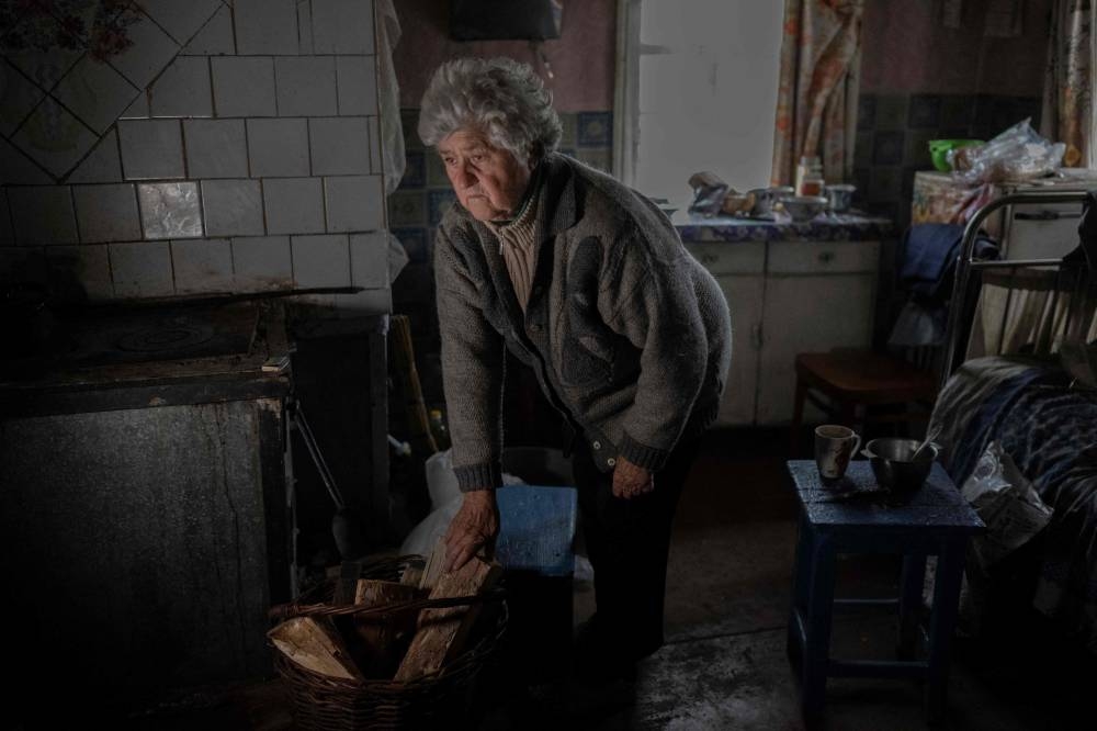 Nina Marchenko puts some wood to light up her stove in her house at the eastern Ukrainian village of Yampil, near the frontline in Donbas region, on November 10, 2022, amid the Russian invasion of Ukraine. ― AFP pic