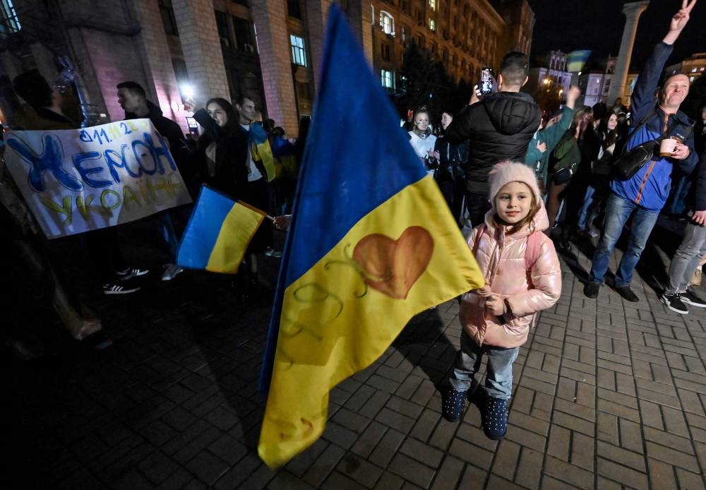 A child holds a Ukranian flag as people gather in Maidan square to celebrate the liberation of Kherson, in Kyiv on November 11, 2022, amid the Russian invasion of Ukraine. ― AFP pic