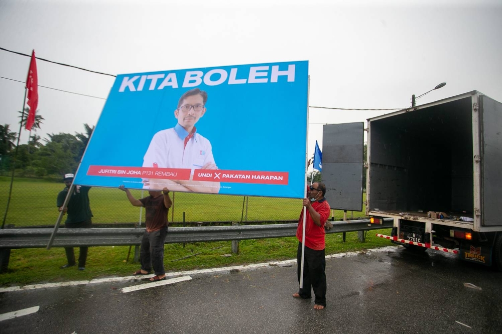 Supporters of Pakatan Harapan set up a billboard of PH candidate Jufitri Joha Hasan in the rain along Jalan Chenong-Astana Raja, Negri Sembilan on November 06, 2022. — Photo by Raymond Manuel