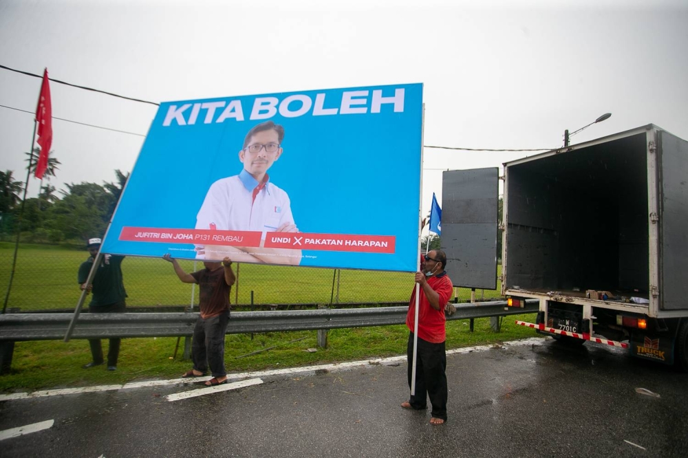 Pakatan Harapan supporters putting up a billboard of PH candidate Jufitri Joha Hasan in the rain along Jalan Chenong-Astana Raja, Negri Sembilan, November 06, 2022 .— Picture By Raymond Manuel