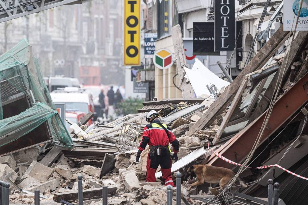 Firefighters inspect a collapsed building as they search for victims in the city of Lille, northern France, on November 12, 2022. — AFP pic
