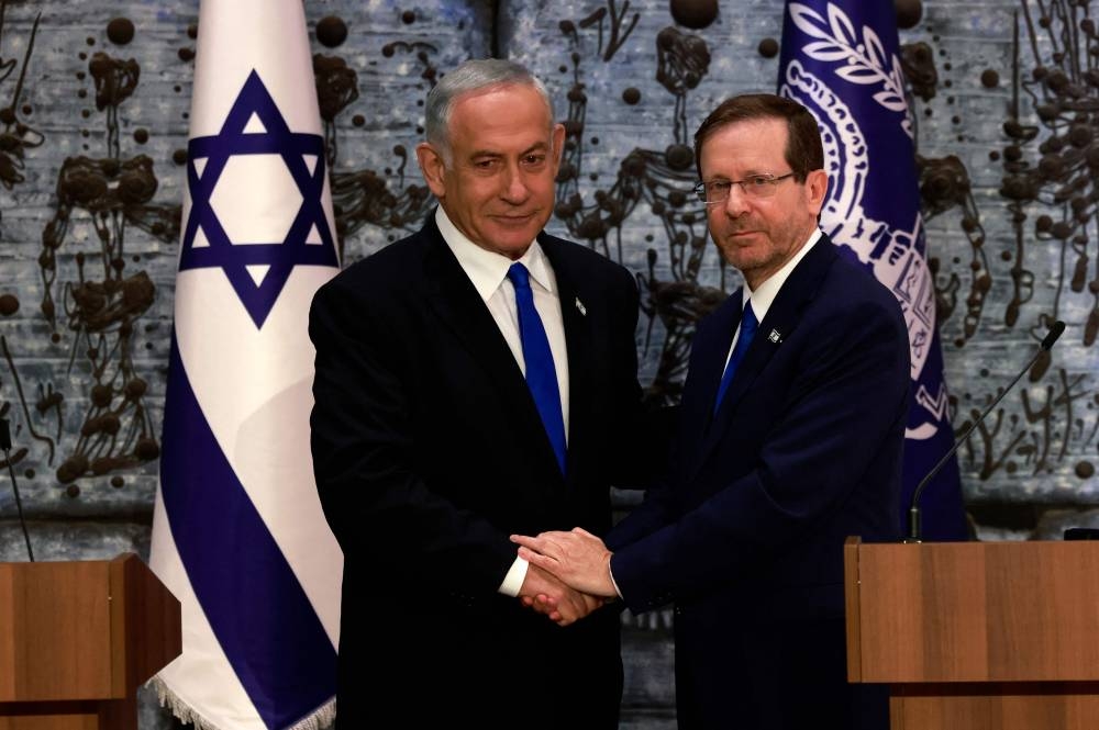 Israel's President Isaac Herzog (R) and Chairman Benjamin Netanyahu shake hands after the former tasked the latter with forming a new government, in Jerusalem, on November 13, 2022. — AFP pic