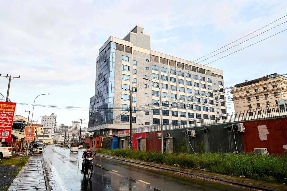 This photo taken on September 26, 2022 shows a motorist passing a building previously shut down by the police, in Sihanoukville in Preah Sihanouk province. — AFP  pic