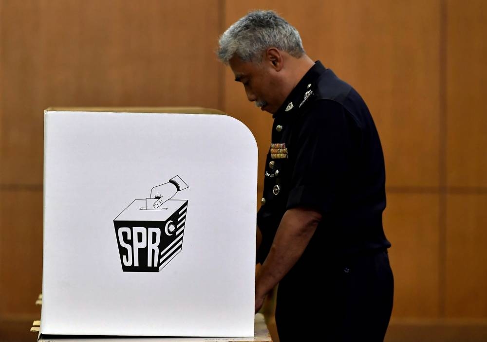 A police personnel checking out the voting booth at the main hall of the Selangor contingent police headquarters as EC staff make final preparations for early voting in Shah Alam, November 14, 2022. — Bernama pic 
