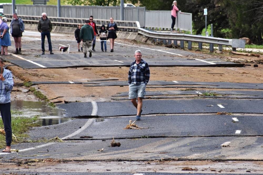People inspect the damaged road following flooding in the town of Canowindra, in the Central West region of New South Wales, Australia, November 15, 2022. — AAP Image via Reuters pic
