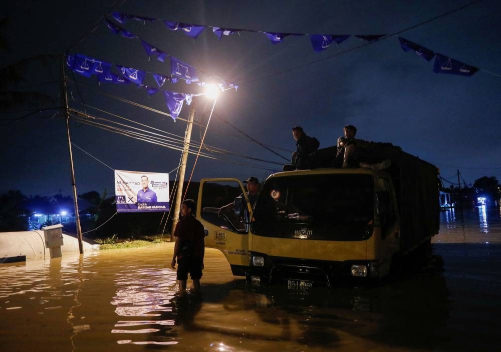 Men waiting for rescue to tow their breakdown truck as party flags are seen above and the election banner of Malaysia’s general election at the back during a flash flood in Klang, Selangor, Malaysia, November 10, 2022. — Reuters pic 