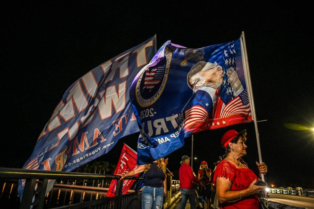 Supporters of former US President Donald Trump hold flags outside Trump’s Mar-A-Lago residence in West Palm Beach, Florida November 15, 2022. — AFP pic